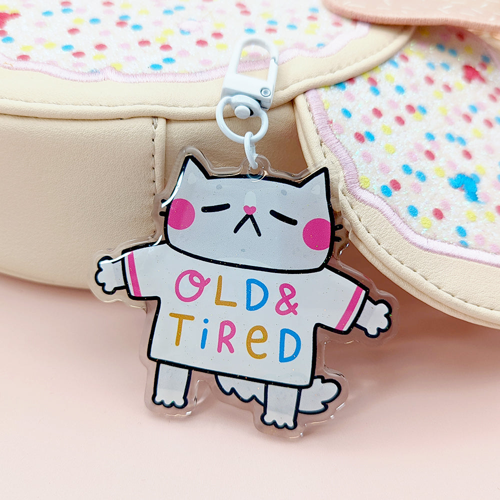 This adorable grey cat keychain has the cutest pink cheeks and features an old and tired tshirt in pink, yellow, and blue!