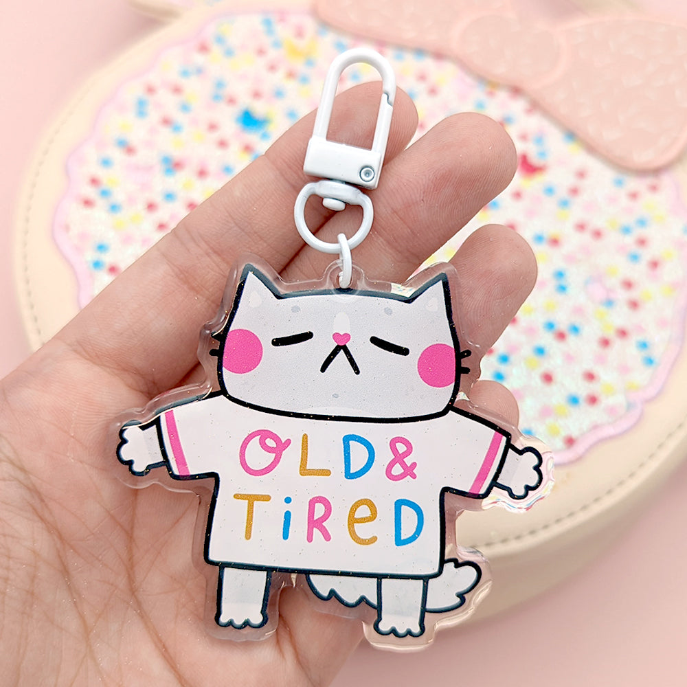 Feeling more old and tired by the day? This keychain gets you. It's got a subtle glitter to the front side, and features a white clasp for attaching to bags.